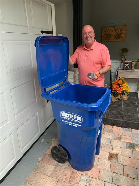 Commissioner Shawn Cerra demonstrating proper recycling with bin